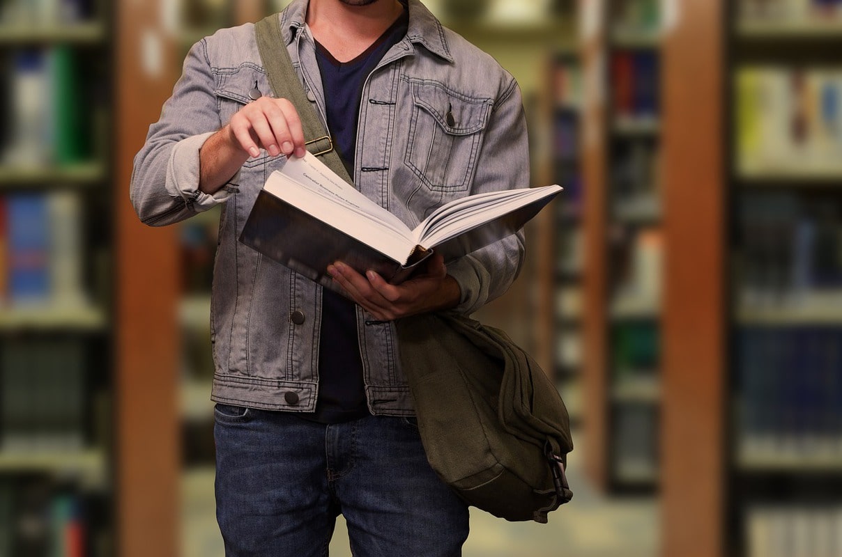 woman carrying white and green textbook